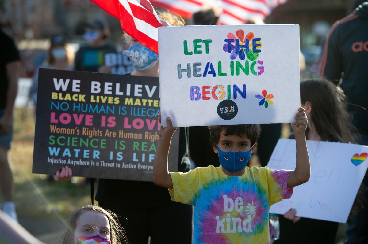 Andrew Reed, right, holds a sign that reads “Let the Healing Begin” at a Biden/Harris victory celebration rally at Mill Creek Park in Kansas City Sunday afternoon, Nov. 8, 2020.