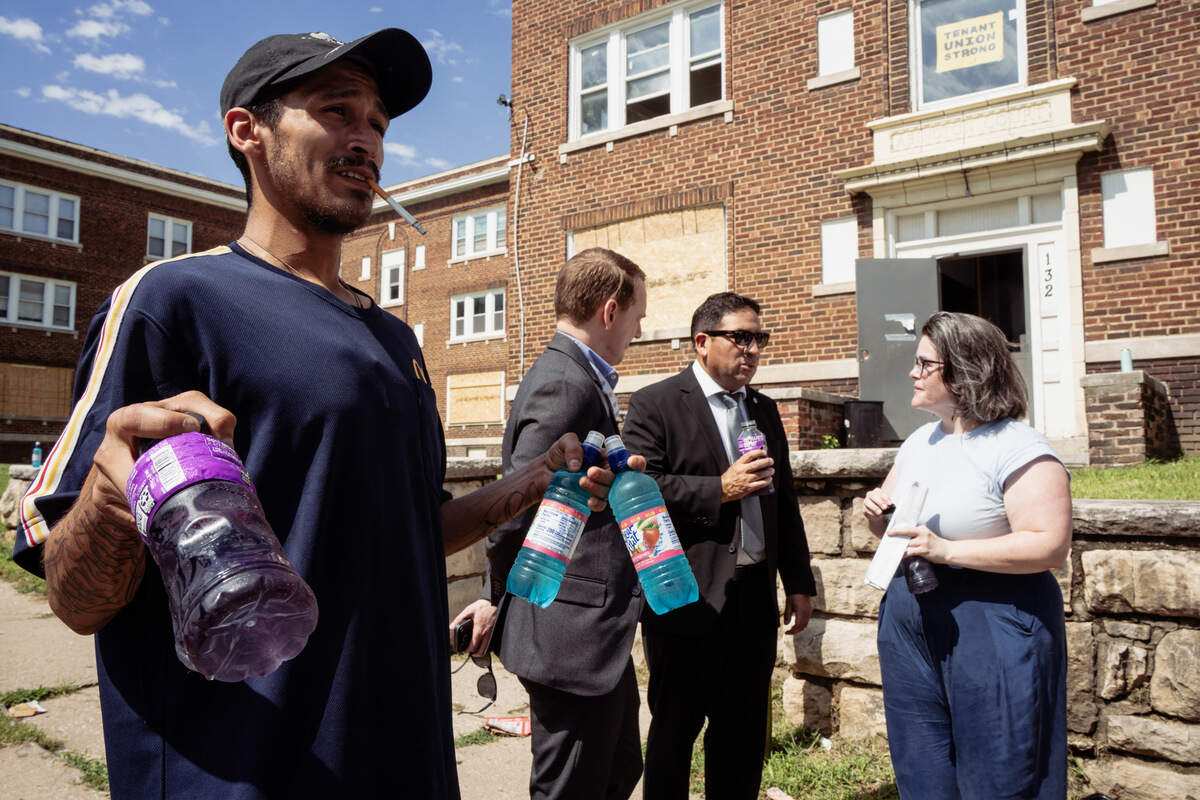 Richard Flores offers drinks to city leaders and staff while they visit an apartment complex on North Lawn Avenue. City Manager Mario Vasquez, center back, is seen speaking to KC Tenants organizer Mary Allison Joseph.