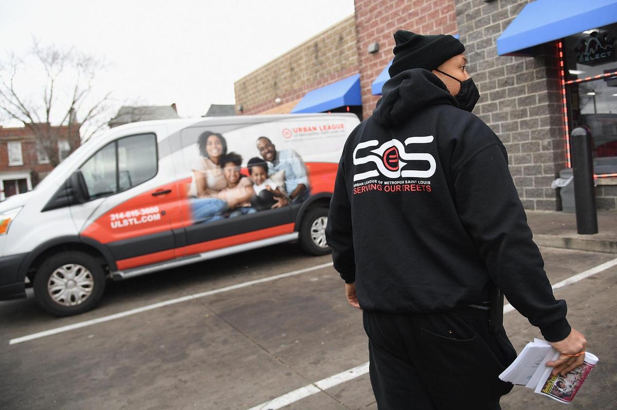 Sean Hughes hands out pamphlets with information about services provided by the “Serving Our Streets” initiative in St. Louis. The group works to help people resolve conflicts and prevent gun violence through a 24/7 hotline and other programs.