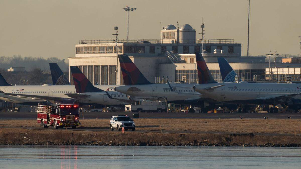 Emergency crews drive past nearby parked passenger planes at Reagan National Airport Thursday after an American Airlines passenger jet with 64 people aboard collided with an Army Black Hawk helicopter near the airport on Wednesday night.