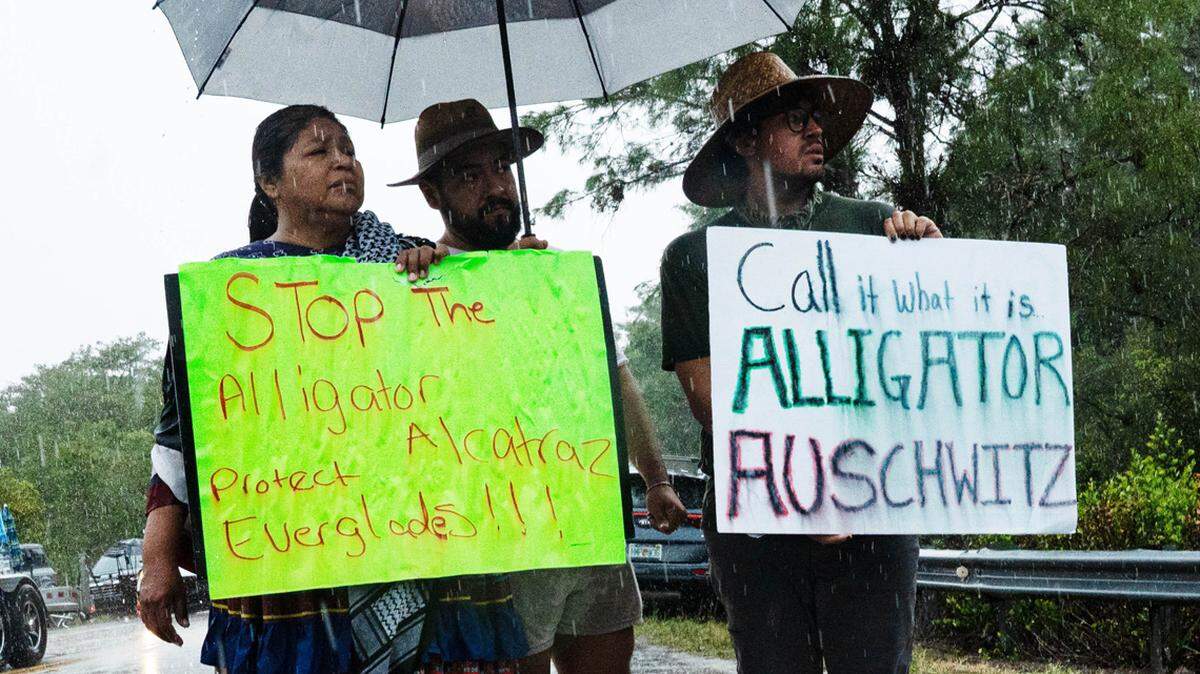 Amy Clay, an independent Seminole protests in the rain at the entrance to the Dade-Collier Training and Transition Airport on Tuesday, July 1, 2025. It is being transformed into a detention center that is known as “Alligator Alcatraz”. President Donald Trump made a visit with Governor Ron DeSantis and others to the site. Media, protestors and supporters gathered outside the entrance.