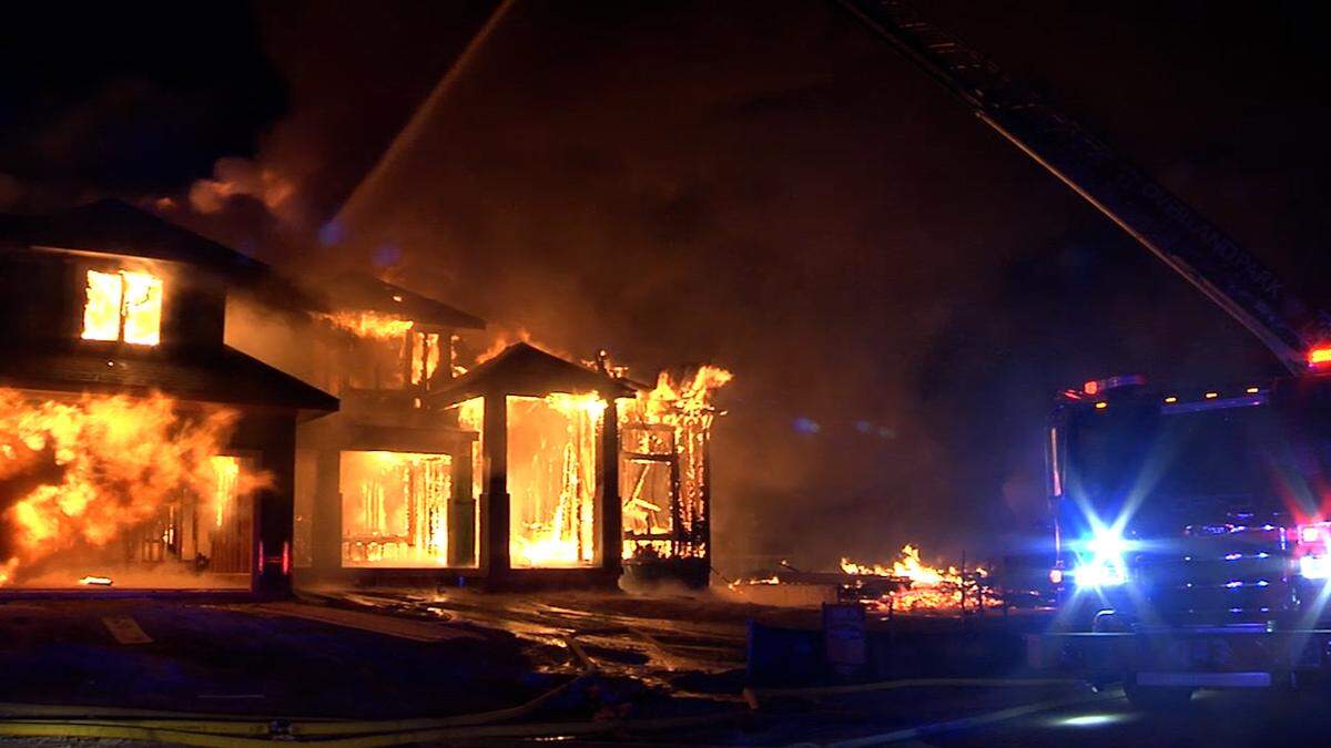 Flames from an overnight fire engulf a house that was under construction in southern Overland Park. The fire destroyed two other homes that were being built and threatened a nearby occupied home.