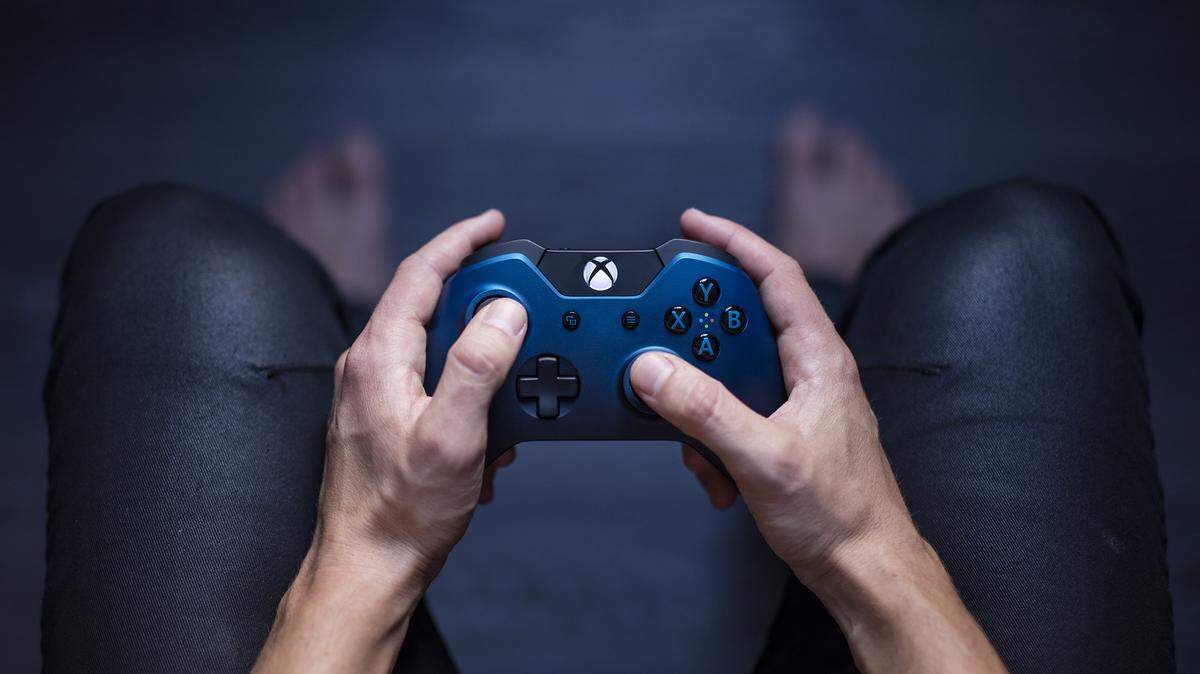 File photo of a young man holding a blue Xbox One controller as he is playing a video game.