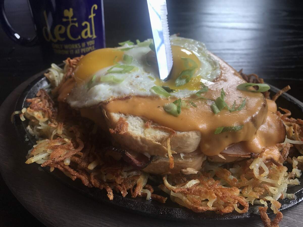The Shack De Madame with honey-glazed ham, thick-cut pecan-wood bacon and white cheddar cheese on Texas toast with cheese sauce, sunny-side-up eggs and green onions served on hash browns for $12.