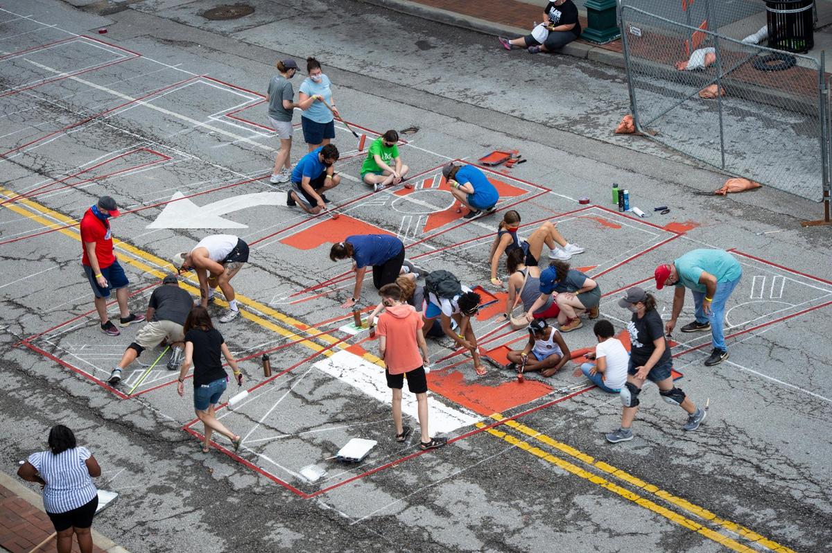 Volunteers worked to fill in giant outlined letters for the Black Lives Matter mural being painted on 10th St. Saturday between Wyandotte and Baltimore.