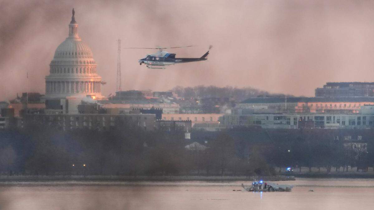 A helicopter flies near the crash site of the American Airlines plane on the Potomac River after the plane crashed on approach to Reagan National Airport on Wednesday in Arlington, Virginia. The American Airlines flight from Wichita, collided with a military helicopter while approaching the airport.
