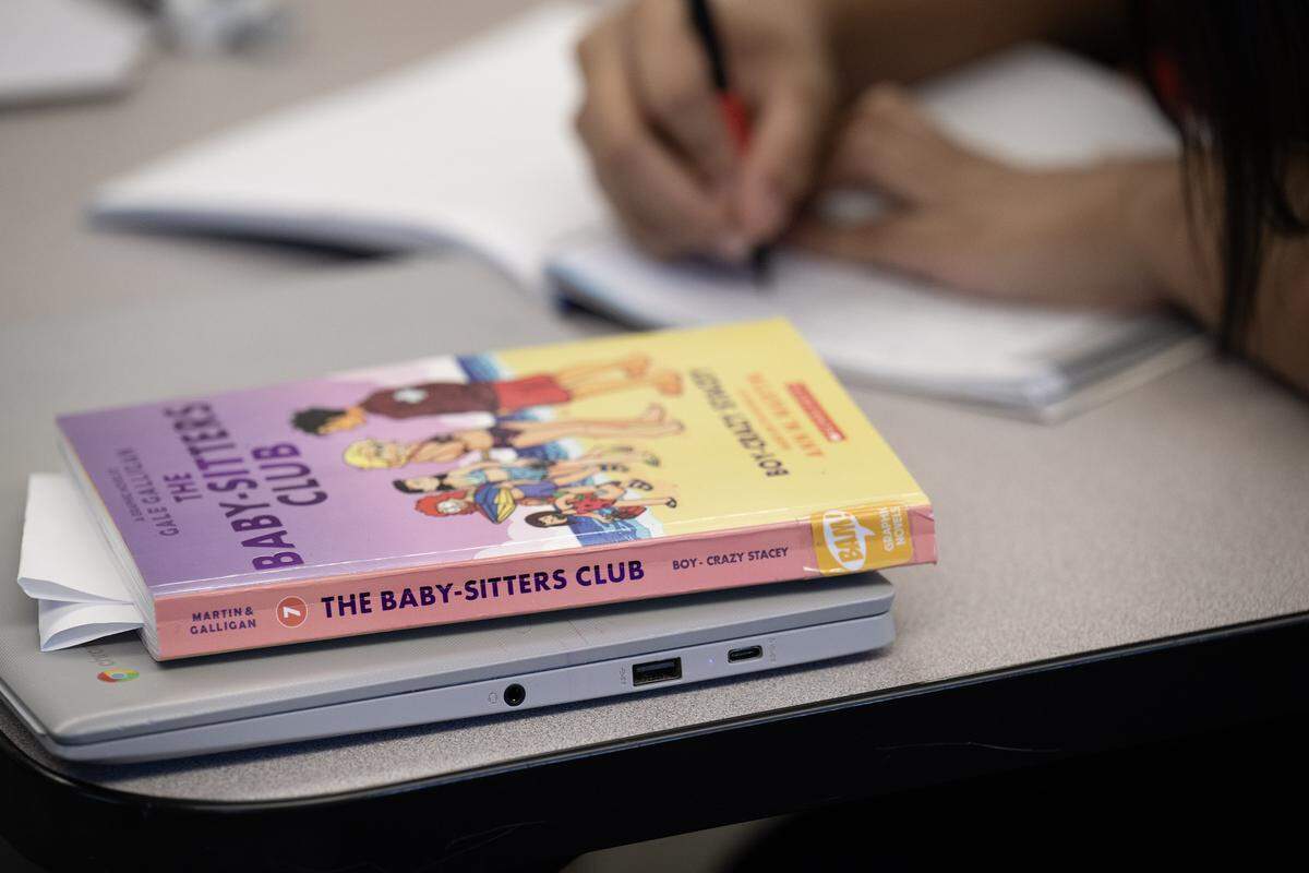 A classroom library book sits on a desk of a seventh-grader during class at Guadalupe Centers Middle School on Thursday, Dec. 4, 2025, in Kansas City. The school does not have a library and Christopher Leavens, an English language development teacher, has started a small library in his classroom for the students to have access to more books.