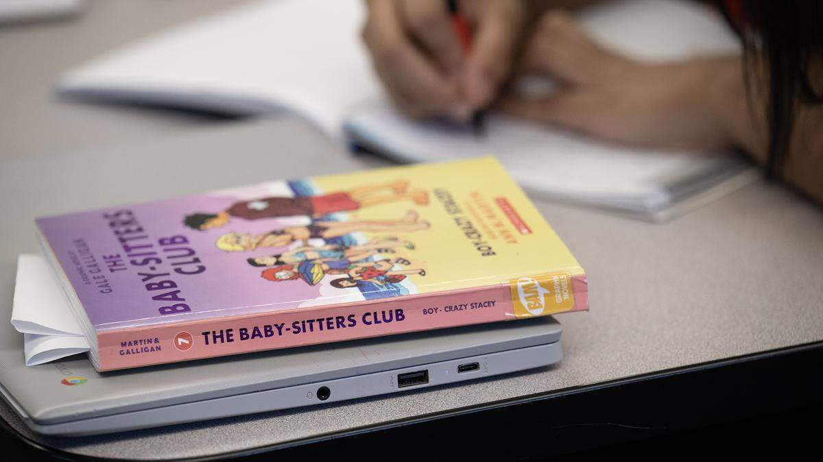 A classroom library book sits on a desk of a seventh-grader during class at Guadalupe Centers Middle School on Thursday, Dec. 4, 2025, in Kansas City. The school does not have a library and Christopher Leavens, an English language development teacher, has started a small library in his classroom for the students to have access to more books.