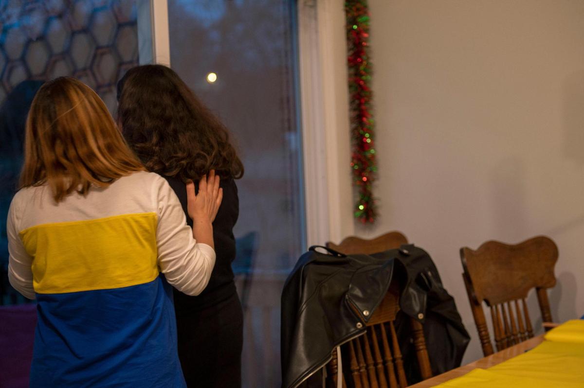 Lyuda Stewart, left, comforts Olga Potapenko, who was updated with news about Ukraine while cutting fabric to make Ukrainian flags at her home in Independence on Thursday, March 3, 2022. Potapenko is a wedding dress designer who has opened her home to help create Ukrainian flags as a thank you to anyone who has donated to support Ukraine.