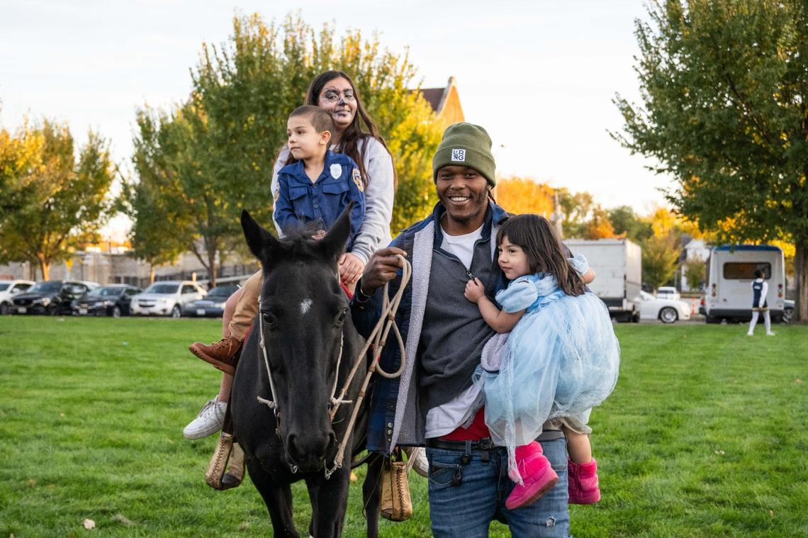 Simeon Brooks carries a young child as he leads two more on ‘Black Jack’ during a trunk or treat event in Kansas City.