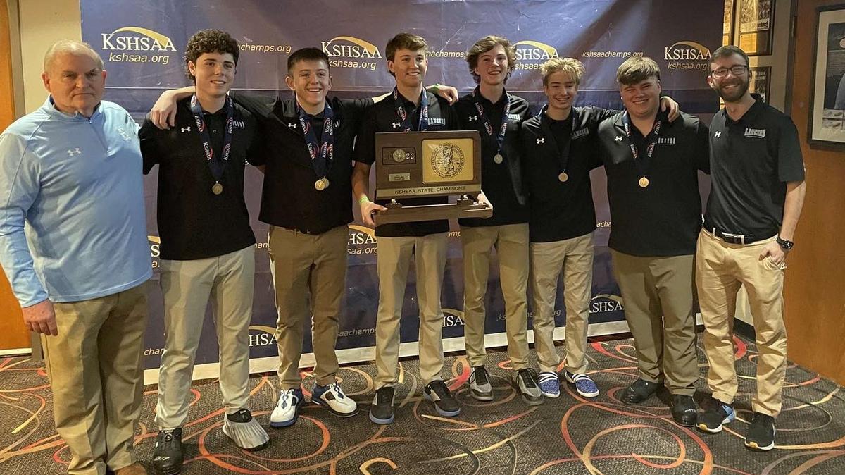 The boys bowling team from Shawnee Mission East shows off the Class 6A state high school bowling trophy accompanying Thursday’s championship.