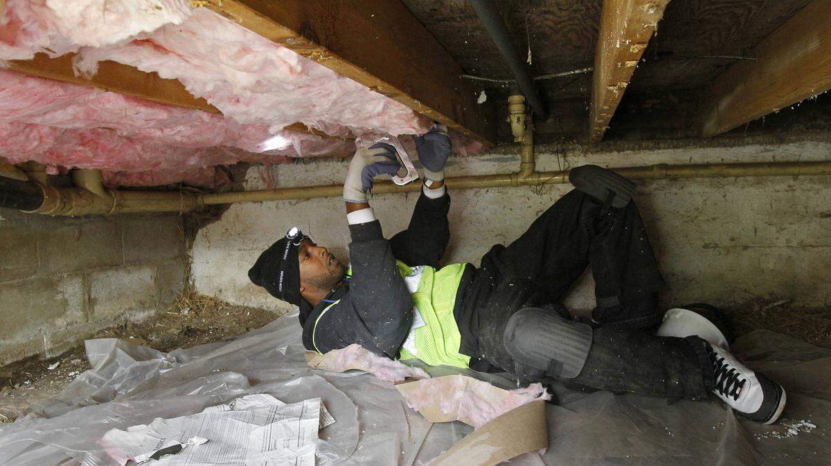 A crew installing insulation in a crawl space under a house on the East Side of Kansas City.