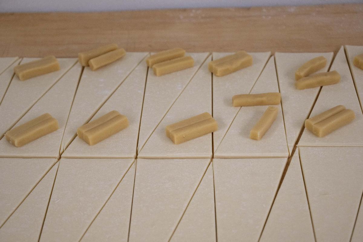 Sticks of marzipan, a mixture of almond meal and sugar, on triangles of dough, waiting to be rolled into almond croissants at Scratch KC.