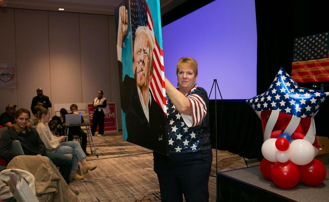Johnson County Republican Party Chair Maria Holiday held up a painting of Donald Trump during a live auction at the Johnson County Republican’s election night watch party at the Marriott Hotel, in Overland Park, Ks.