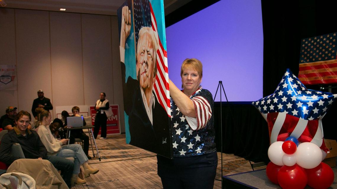 Johnson County Republican Party Chair Maria Holiday held up a painting of Donald Trump during a live auction at the Johnson County Republican’s election night watch party at the Marriott Hotel in Overland Park.