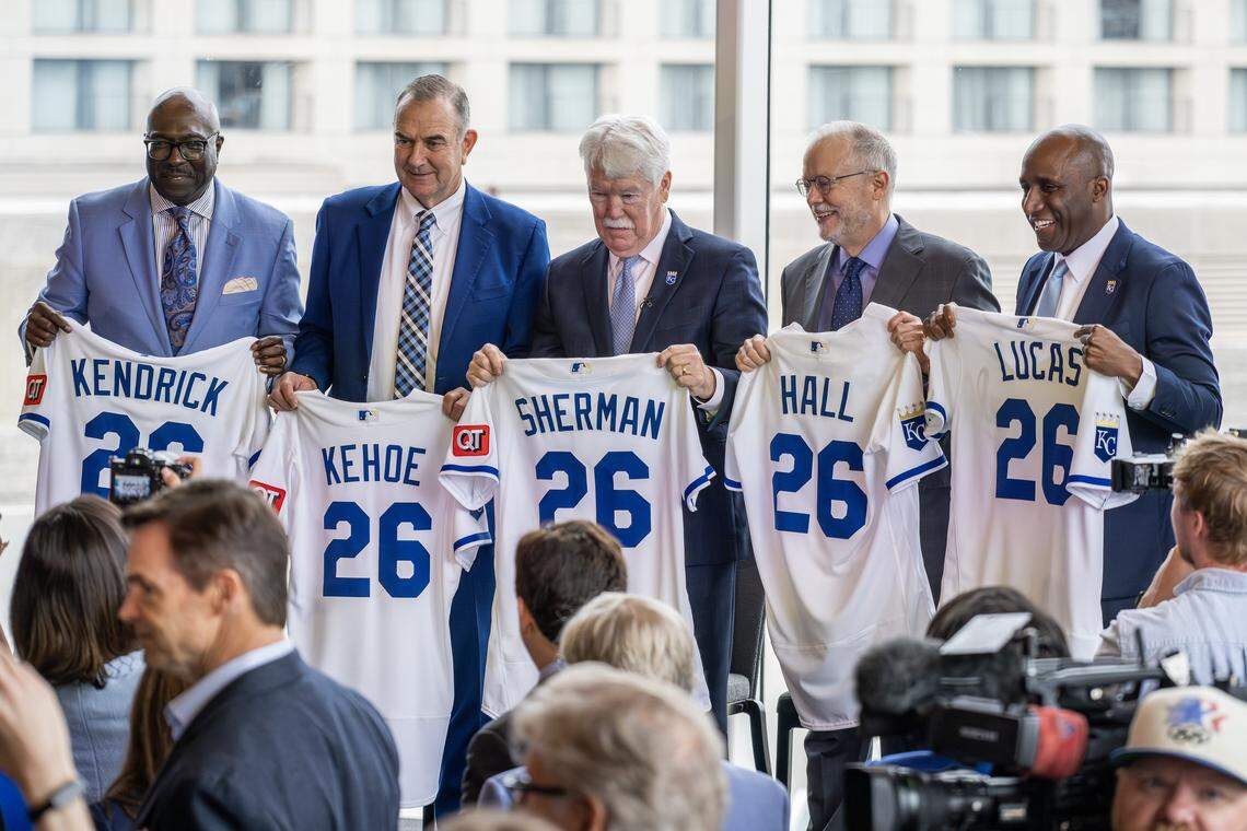 Bob Kendrick, president of the Negro Leagues Baseball Museum, left, Missouri Gov. Mike Kehoe, John Sherman, chairman and CEO of the Kansas City Royals, Donald J. Hall Jr., executive chairman and former CEO of Hallmark Cards and Kansas City Mayor Quinton Lucas, laugh while holding Kansas City Royals jerseys during a ceremony announcing the team's move to Crown Center on Wednesday, April 22, 2026, in Kansas City.
