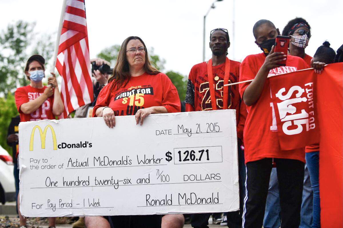 Monica Roberts, 46, holds a large, fake check as she stands with roughly 100 people gathered Wednesday, May 19, 2021, to demand union rights and a $15 minimum wage for fast food workers at a McDonald’s on Main Street in Kansas City.