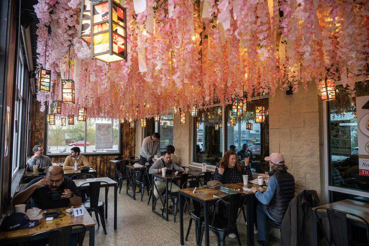 Guests dine beneath decorative hanging faux flowers and lanterns at KC Craft Ramen on Wednesday, Oct. 29, in Overland Park.