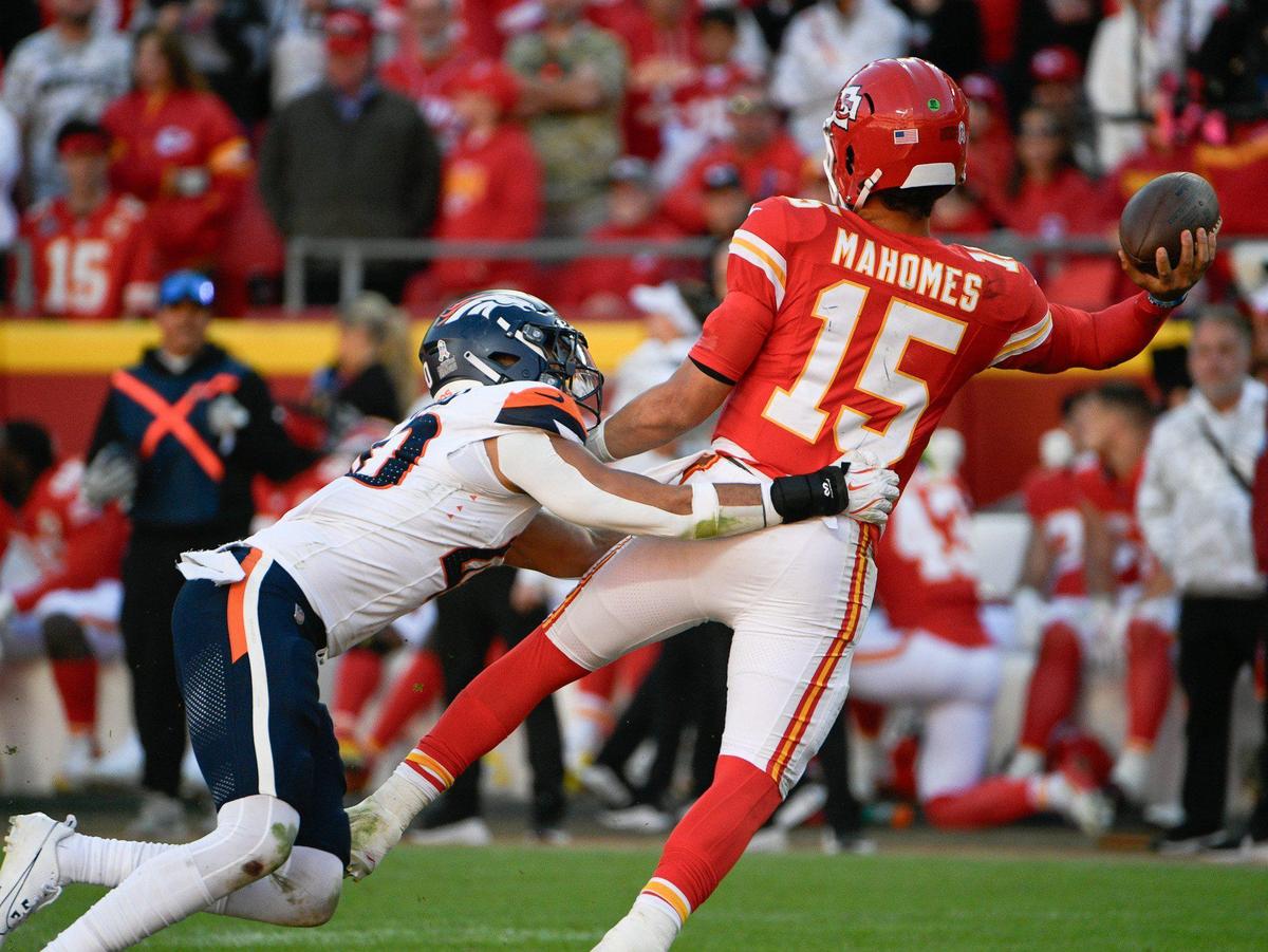 Kansas City Chiefs quarterback Patrick Mahomes (15) throws a pass while in the grasp of Denver Broncos linebacker Justin Strnad (40) on Sunday, Nov. 10, 2024, at GEHA Field at Arrowhead Stadium.