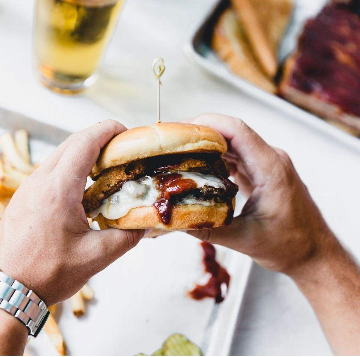 County Road Ice House’s Z-Man Burger has two fresh chuck and smoky brisket blend patties topped with smoked provolone, onion rings, and Joe’s Original BBQ Sauce.