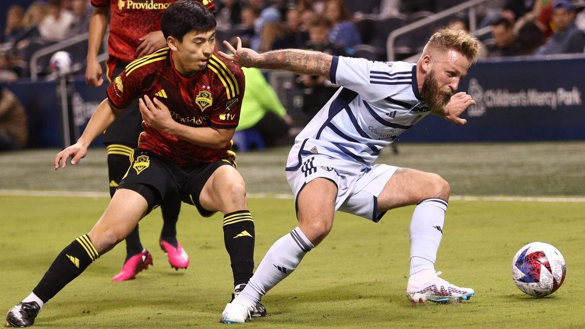 Sporting Kansas City forward Johnny Russell, right, tries to hold off Seattle Sounders midfielder Sota Kitahara during Saturday’s match at Children’s Mercy Park.