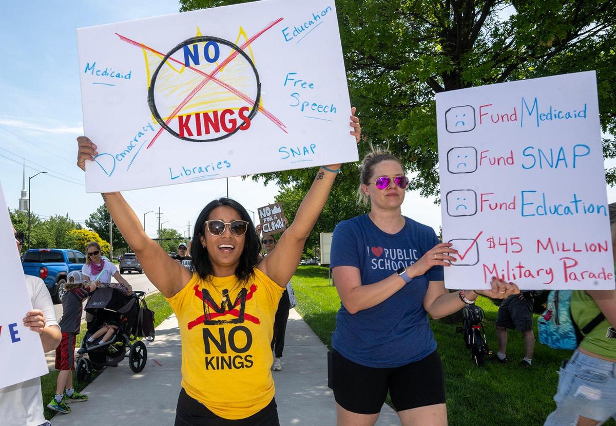 Protesters Rhea Le Grande of Lenexa, left, and Ellen Jorgenson of Parkville, marched and rallied as part of a nationwide “No Kings” day of defiance on Saturday, June 14, 2025, in Lenexa, Kansas. The events protest President Donald Trump and immigration policies, among other issues.