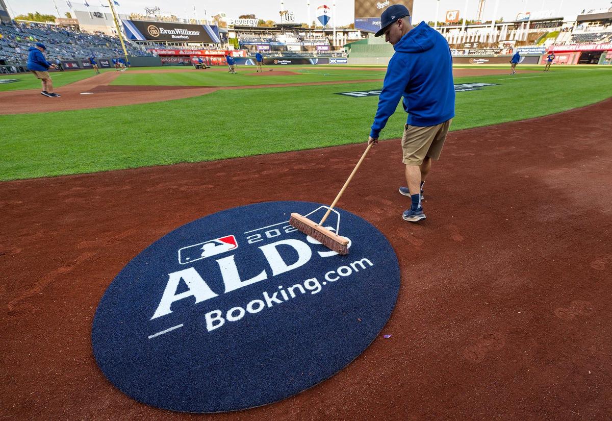 A member of the grounds crew sweeps up around the ALDS logo on the field before Game 3 of the American League Division Series on Wednesday, Oct. 9, 2024, at Kauffman Stadium in Kansas City.