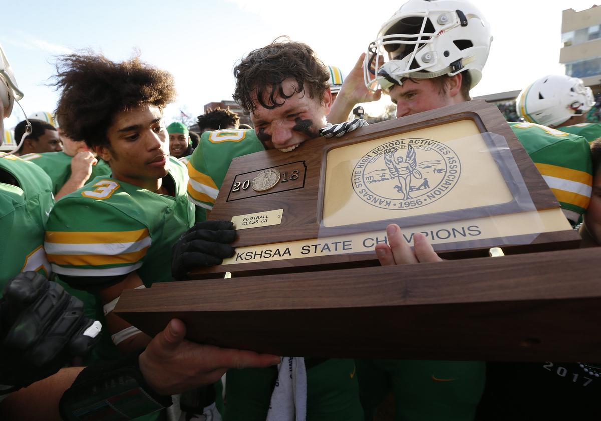Derby High defender Dax Benway celebrates their 6a State Championship by leaving bite marks in the Championship Trophy Saturday afternoon in Emporia.  Derby beat Blue Valley North 24-16 (November 24, 2018)