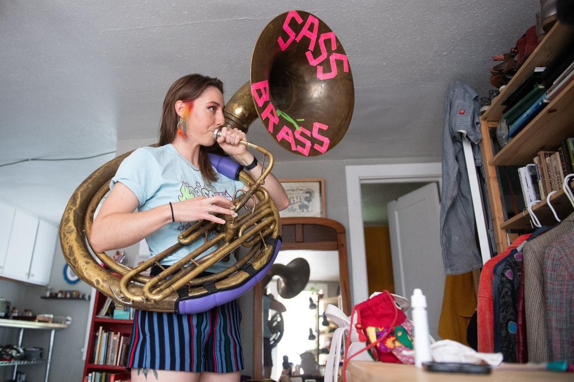 Sass-A-Brass band leader and sousaphonist Rosie O’Brien warms up her instrument in her attic apartment prior to the City Market Pride month celebration.