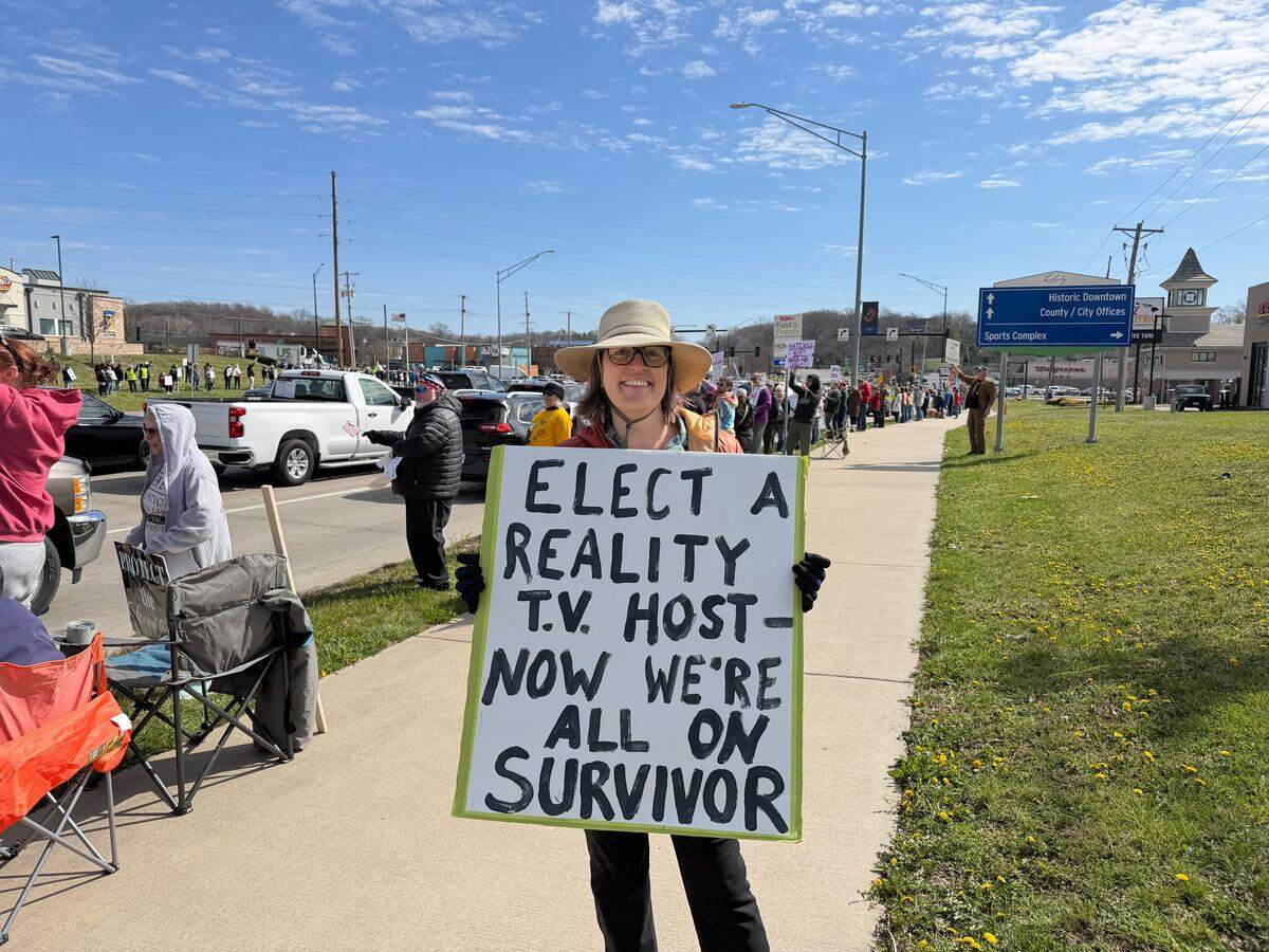 Analisa Lee holds a sign reading, “Elect a reality TV host — now we’re all on Survivor,” during a No Kings protest in Liberty on Saturday, March 28.
