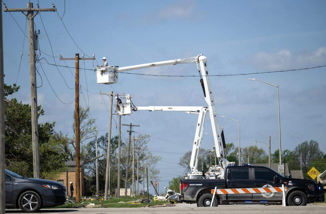 Utility crews work to repair downed power lines along 17th Street in Ottawa, Kansas, on Tuesday, April 14, 2026. A tornado struck the city Monday night causing significant damage, but no injuries.