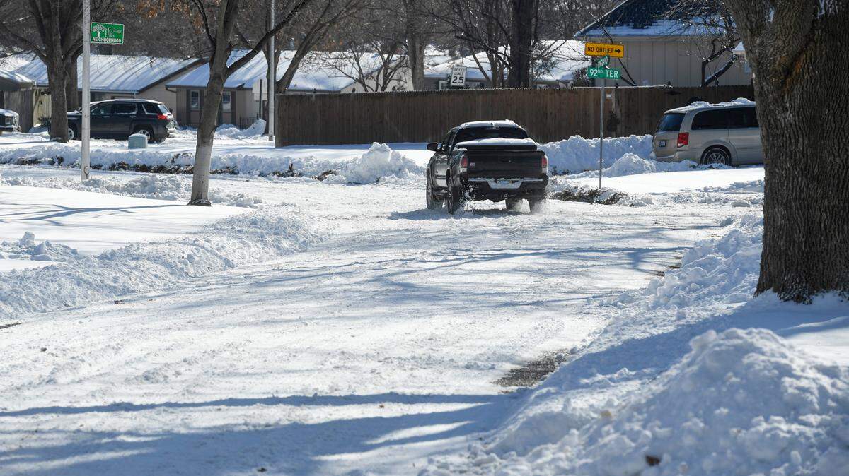 A vehicle makes its way along a snow packed England Street in Overland Park on Tuesday, Jan. 7, 2025. Overland Park officials say the city plans to have streets cleared of the nearly foot of snow that fell over the weekend by Wednesday.