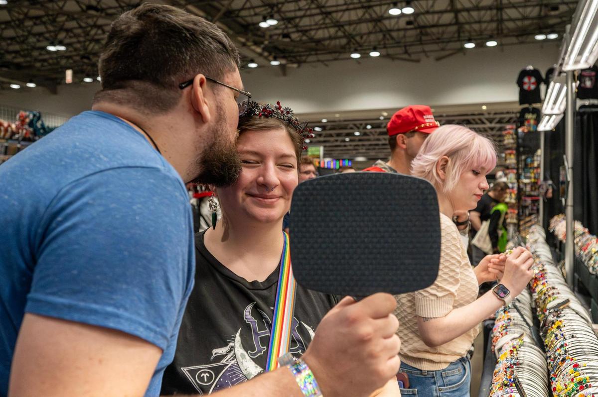 Connor Joyce kisses his wife Eli Cave while trying on a tiara at the Whirl and Twirl Headbands booth during Planet Comicon at the Kansas City Convention Center on Saturday, March 22.