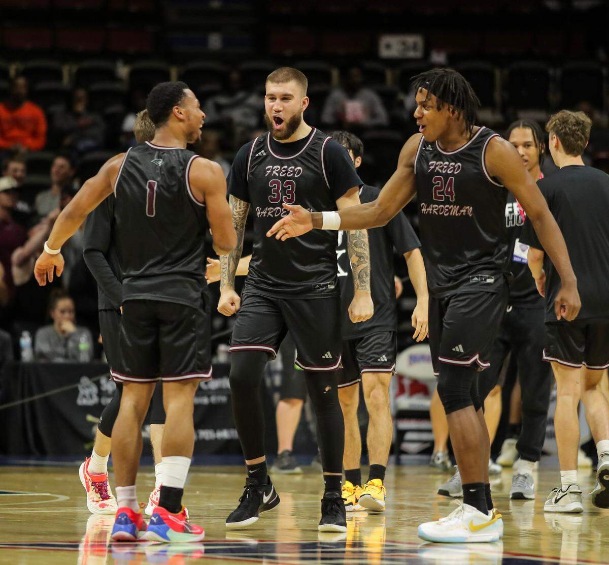 Devin Tomlinson, middle, celebrates with Freed-Hardeman teammates Phil Horton, right, and JJ Wheat after the final buzzer sounds on Monday night’s NAIA semifinal game against Grace College. Freed-Hardeman outlasted the Lancers 86-81.