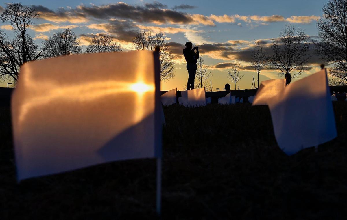 A visitor takes photos of the display. People who lost their lives to COVID-19 were remembered and frontline workers were honored on the National Day of Remembrance Tuesday, Jan. 19, 2021. A white flag for each of the 1,665 people who died of COVID in the Kansas City metro area was planted in front of the National World War I Museum and Memorial and the city skyline was lit in amber. This coincided with ceremonies across the country. A visitor takes photos of the display.