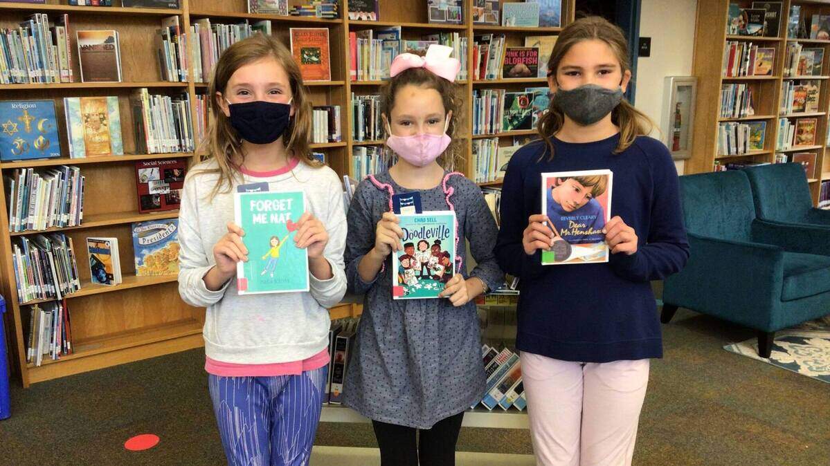 Evie Joblin, Parker Falley and Isla Roberson show their book club picks at Belinder Elementary.