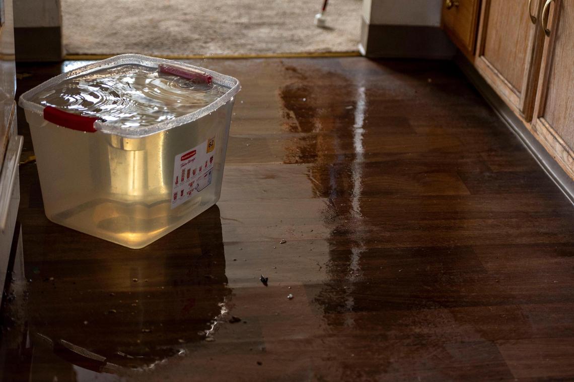 Water collects in a plastic container from a collapsed ceiling in Darrin Sherman’s apartment in Kansas City on Tuesday, April 12, 2022. Sherman, a resident of Parade Park Homes, recently left his home after his water heater went unfixed for months, causing a major leak and partial collapse of his ceiling.