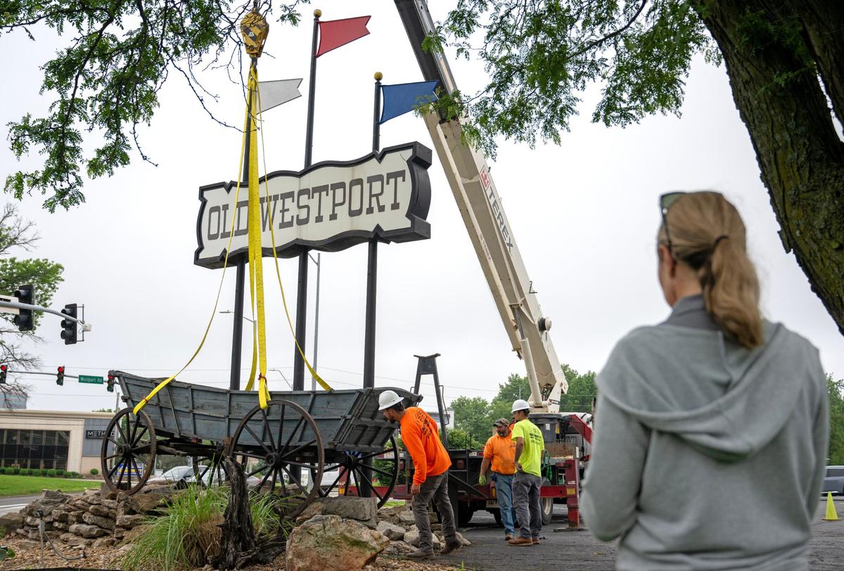Mercedes Chastain watches as crews from Infinity Sign Co. lower a replacement wagon at Old Westport Shopping Center on Wednesday. The replica, built in 1976, replaces the 1860s covered wagon that had stood there since 1963. Chastain’s father, Copper Weeks, owns the shopping center, and she and her brother run it.