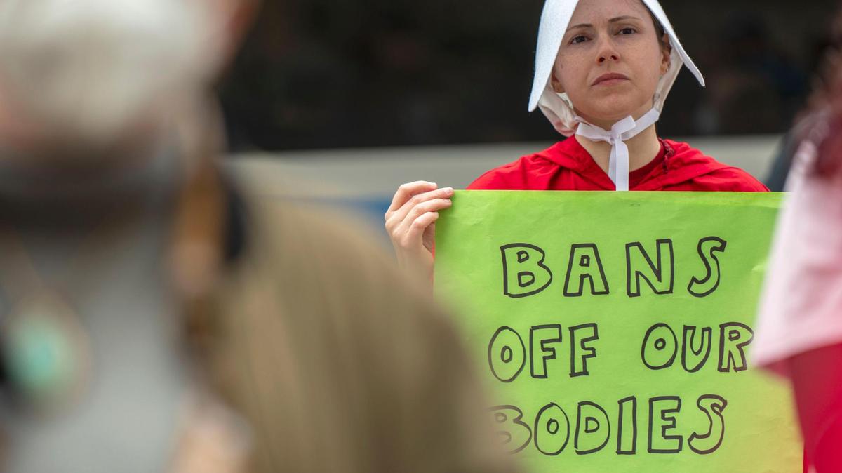 Jennifer Seward dressed as a character from the television show “The Handmaid’s Tale” while protesting Tuesday outside of the Jackson County Courthouse. Protesters were there to show their support for reproductive rights after it was reported that a leaked document showed the Supreme Court has voted to overturn Roe v. Wade.