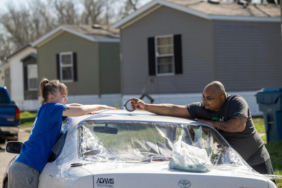 Tricia and Miguel Clark of Edwardsville, Kansas, cleaned up glass and secured the window of their teenagers’ car Thursday after the back window was shattered by hail Wednesday night as severe storms moved through the Kansas City metro area.