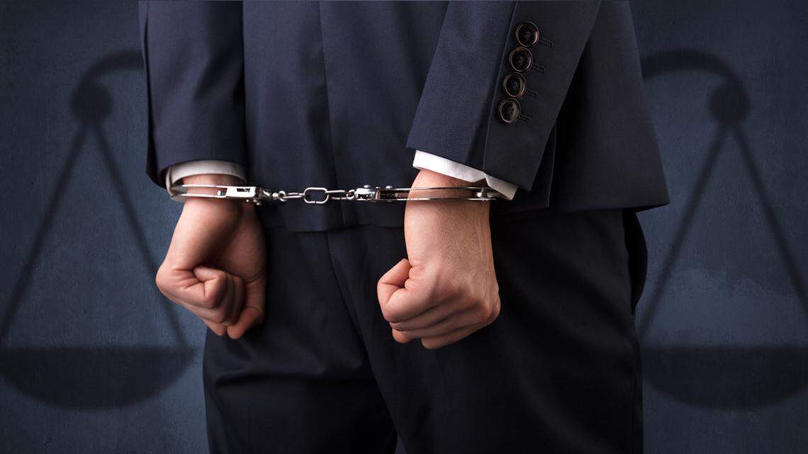 Arrested businessman in handcuffs with hands behind back justice arrest police law