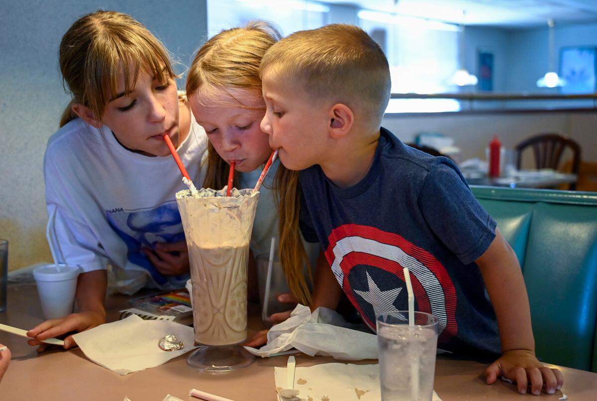 Anna Scher, 12, from left, and her cousins Raylan Kreher, 6, and Remington Kreher, 4, share a Skyscraper Shake at Winstead’s in Kansas City. The restaurant dates to 1940.