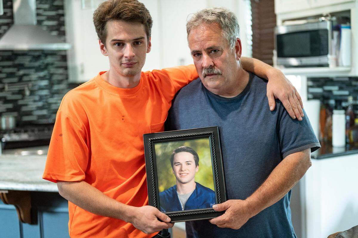 Trey Keating, left, and his father, Robert Keating, hold a photo of Kyle A. Keating, a brother and son to the pair, who died as a result of an accident with a RideKC Bus. Kyle was killed in the crash March 3 near the RideKC park and ride transit center at 75th Street and Prospect Avenue.