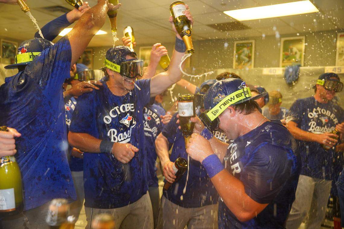 Inside the visiting team’s clubhouse at Kauffman Stadium in Kansas City, Toronto Blue Jays players celebrate having clinched a playoff berth after beating the Royals 8-5 on Sunday, Sept. 21, 2025.