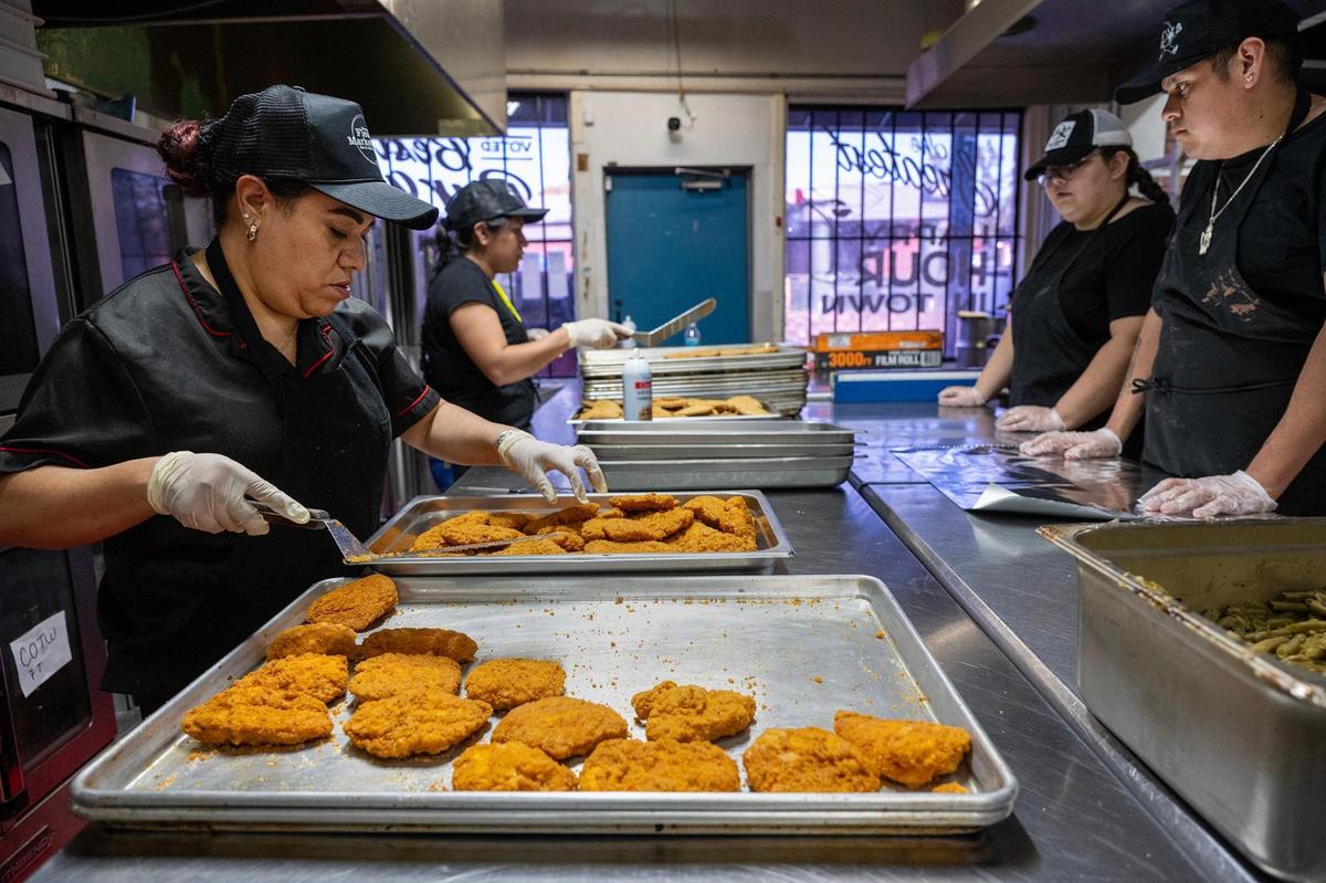 Claudia Vega, left, and others prepare spicy chicken patties for a school lunch, part Joe Joe’s Catering at the Westport Flea Market.