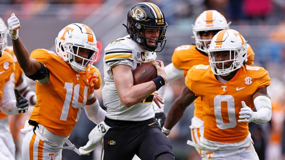 A horde of Vols surrounds Missouri Tigers quarterback Brady Cook as he scrambles for yardage during Saturday’s game in Knoxville, Tenn.