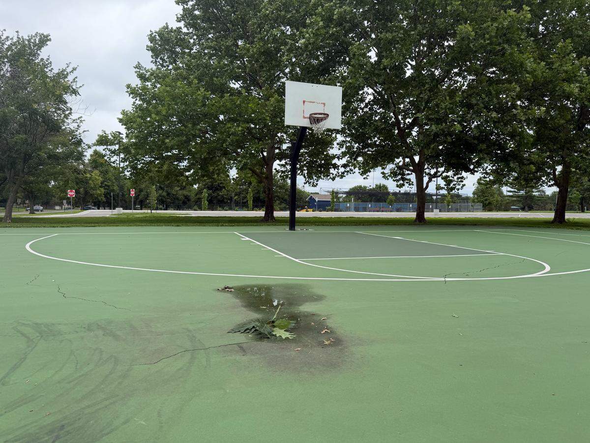Rainwater and debris cover a cracked basketball court in Olathe at Black Bob Park. 