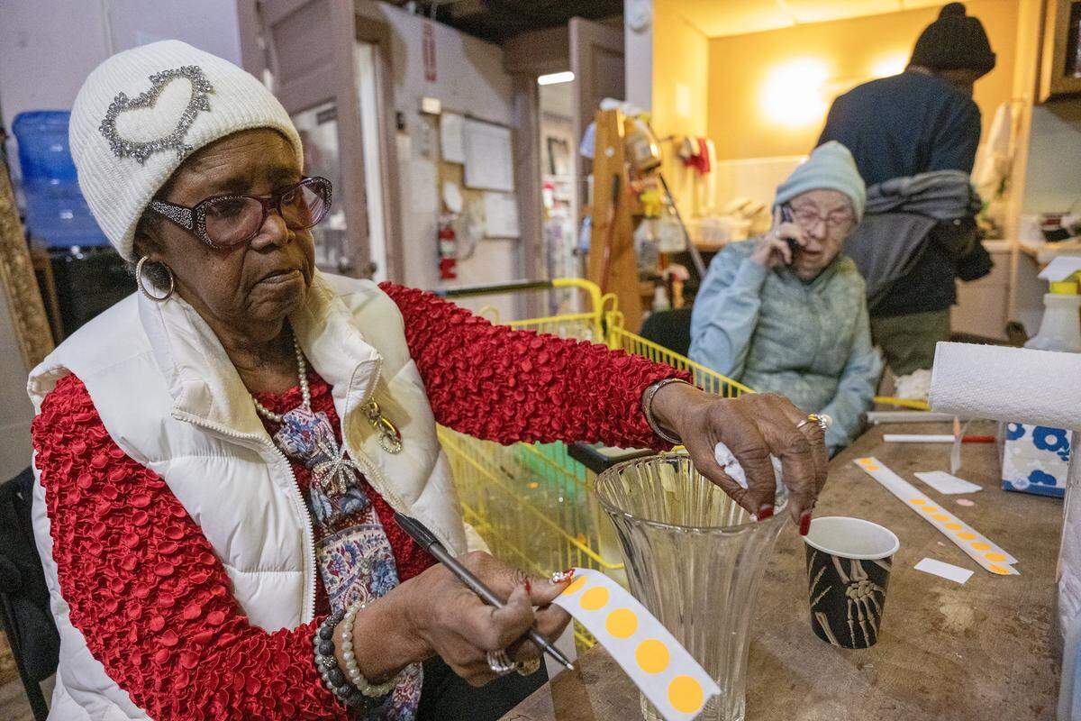 Jane Fowler, 82, who works at Troost39, a thrift store, prices glassware on Thursday, Jan. 22 2026, in Kansas City. Fowler has worked at the store for about two years and says she loves to help customers pick out outfits.