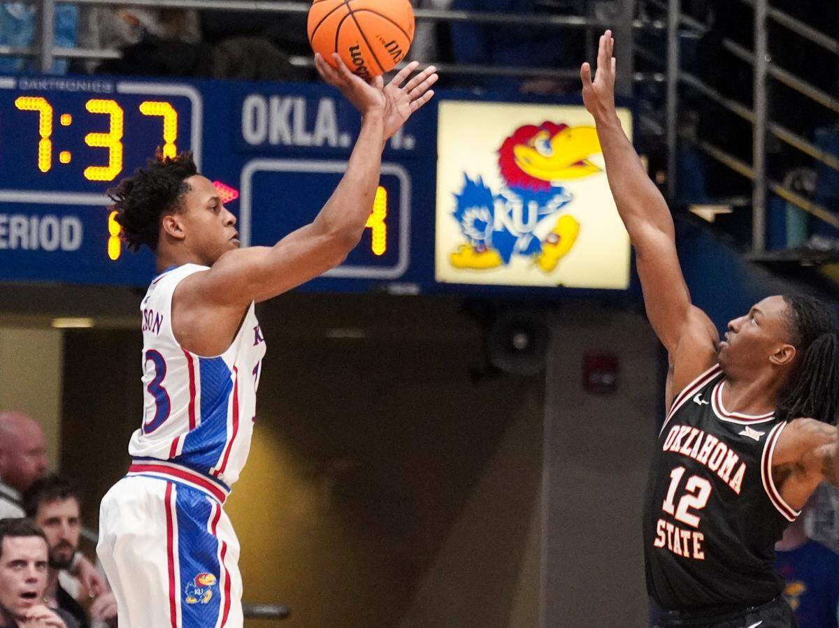 Kansas Jayhawks guard Elmarko Jackson (13) shoots a 3-pointer as Oklahoma State Cowboys guard Javon Small (12) defends during the first half at Allen Fieldhouse on Jan. 30, 2024.