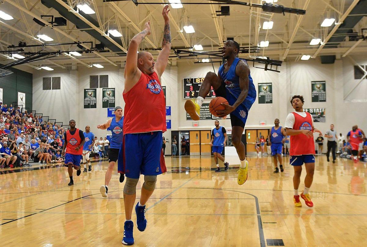 Former KU guard Tyshawn Taylor gets fancy with an attempted layup over Greg Ostertag during Thursday night’s Rock Chalk Roundball Classic at Free State High School in Lawrence.